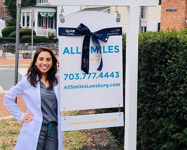 Dentist standing next to dental office sign