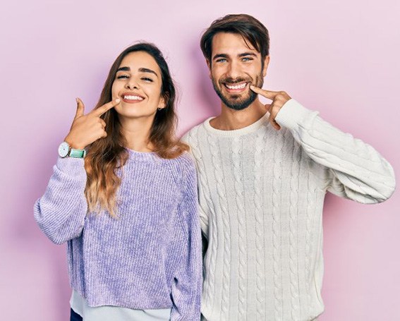 Happy young couple pointing at their teeth
