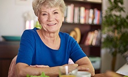 Senior woman smiling and sitting at table for meal