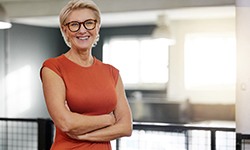 Senior woman in office smiling with arms folded