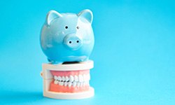 piggy bank lying on a model of teeth