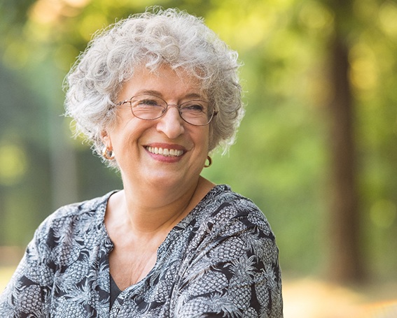Senior woman with glasses smiling outside