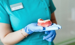 Dental expert with gloves holding dentures