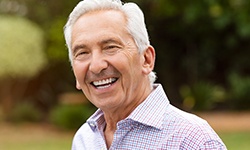 Senior man with white hair smiling outside