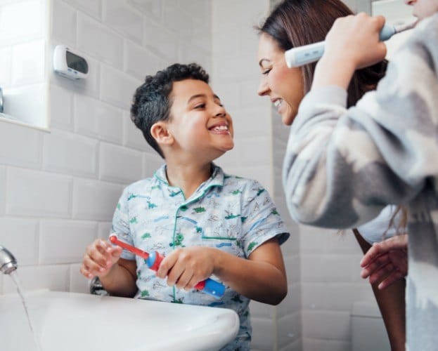 Mother and children brushing teeth to prevent dental emergencies