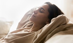 a woman taking a nap after undergoing dental implant surgery