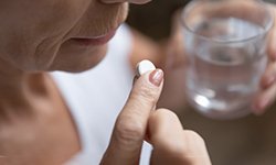 a person taking a pain reliever after dental implant surgery