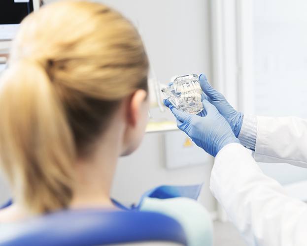 Dentist describing the four step dental implant process