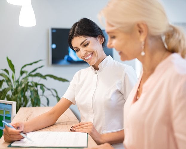 Woman taking to dental team member at front desk