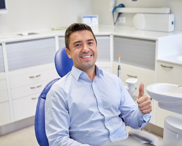Male dental patient smiling and giving thumbs up