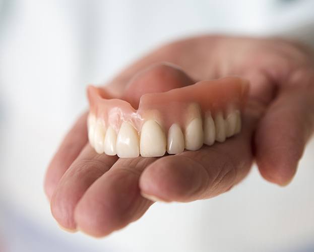 Hand holding a full denture