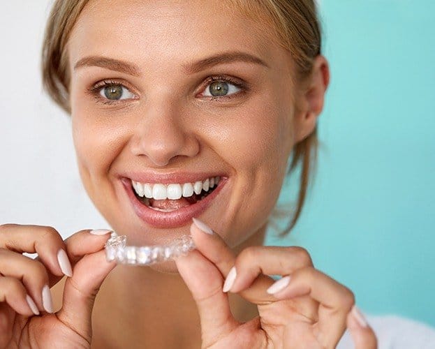 Smiling woman placing an Invisalign tray