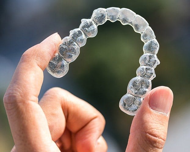 Hand holding a SureSmile clear aligner