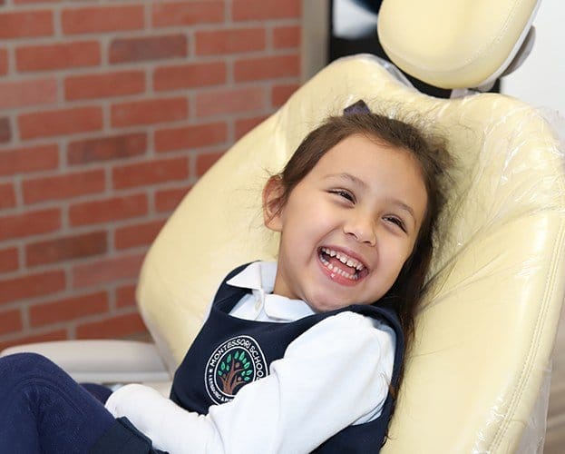 Child laughing during preventive dentistry checkup and teeth cleaning visit