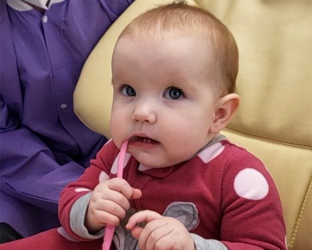 Baby chewing on toothbrush in dental chair