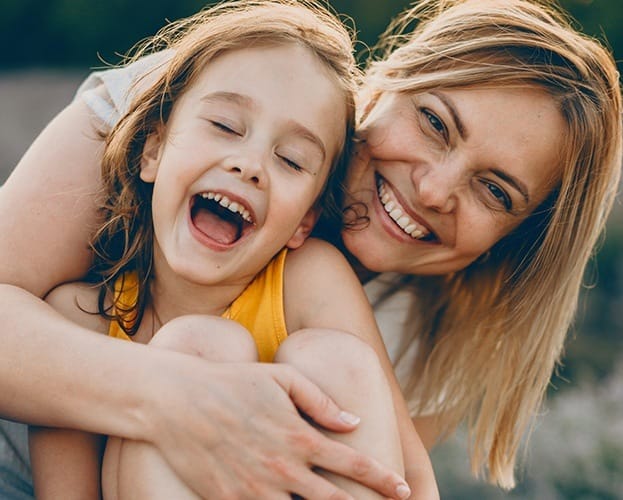 Mother giving child a hug after dental sealant placement