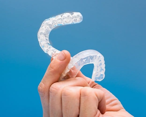 Hand holding clear nightguards for teeth grinding