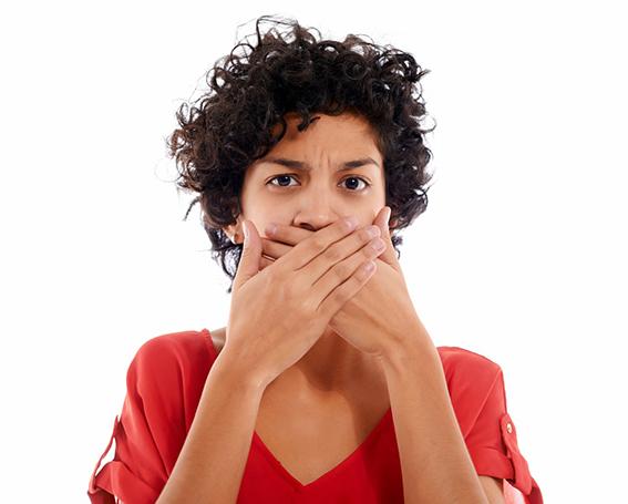 Woman standing against white background, covering her mouth