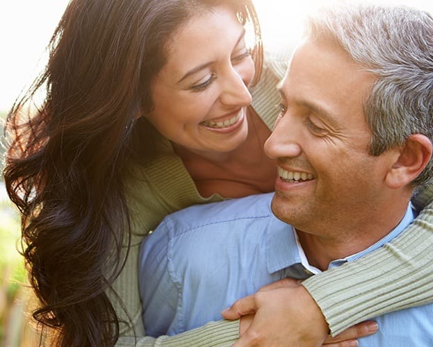 Man and woman smiling together after full mouth reconstruction