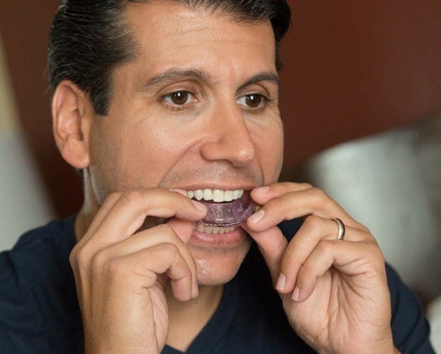 Man placing oral appliance for sleep apnea therapy