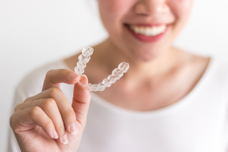 young woman holding an Invisalign aligner
